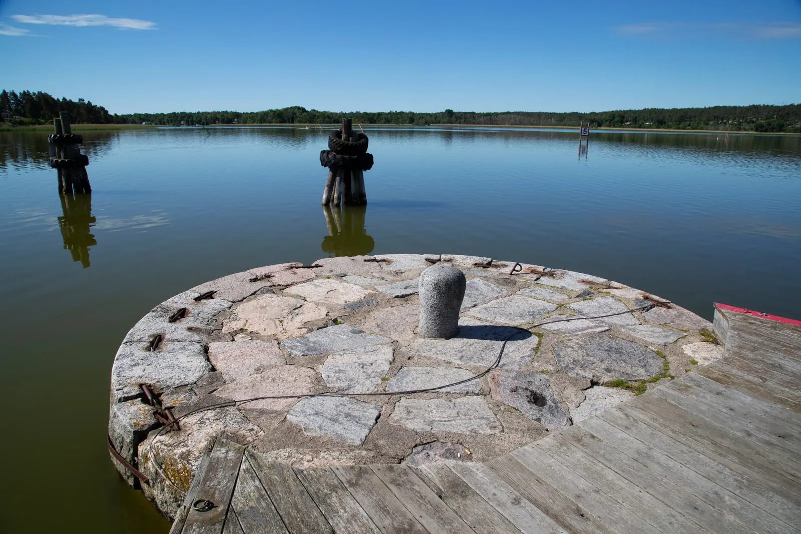 Stenkaj med pollare i en lugn vik i Trosa skärgård